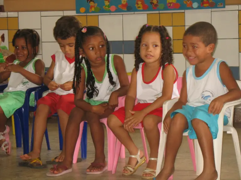Bambini della scuola dell'infanzia seduti in fila sulle panche